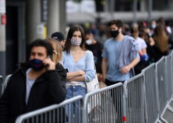 PENDUDUK beratur untuk menerima suntikan vaksin Covid-19 di luar sebuah
pusat vaksinasi sementara yang ditubuhkan di Stadium Emirates di utara London. - AFP