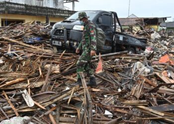 ANGGOTA tentera berjalan di sebalik kesan tsunami di Sumber Jaya, Banten, tiga hari selepas berlaku tsunami pada 2018. - AFP