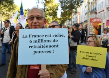 SEORANG penunjuk perasaan memegang sepanduk bertulis 'Perancis kaya, tetapi enam juta orang bersara miskin.'-AFP