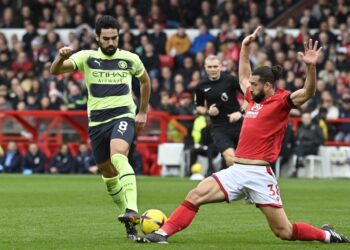 Pemain tengah Manchester City, Ilkay Gundogan (kiri) sedang melepasi kawalan ketat pemain Nottingham Forest dalam saingan Liga Perdana Inggeris di Stadium City Ground sebentar tadi. (Foto: AFP)