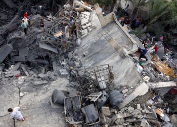 PENDUDUK Palestin melihat bangunan yang runtuh akibat terkena bedilan serangan udara Israel di utara Gaza. - AFP