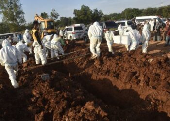 PETUGAS memakai sut perlindungan diri ketika melakukan pengebumian di Bekasi, Indonesia. - AFP