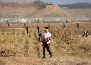 SEORANG lelaki mengangkat remaja yang cedera dalam serangan tentera rejim Zionis ketika demonstrasi di Gaza City. - AFP