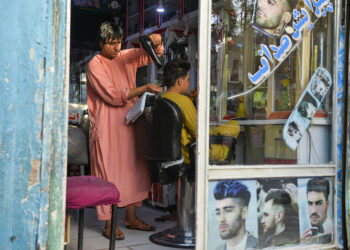 NADER Shah menggunting rambut pelanggan di kedainya di Herat. - AFP