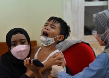 A child receives the Sinovac Covid-19 vaccine at an elementary school in Jakarta on December 15, 2021, as part of a government programme to vaccinate children aged 6 to 11. (Photo by ADEK BERRY / AFP)
