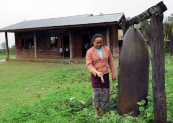 GURU di Laos kreatif menggunakan bangkai bom  sebagai gong gergasi yang berfungsi sebagai loceng menghiasi pintu masuk sekolah. – AFP