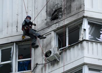 PAKAR memeriksa bangunan pangsapuri bertingkat yang rosak akibat serangan dron di Moscow kelmarin.-AFP