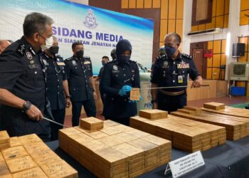 RAZARUDIN HUSAIN (kanan) menunjukkan ketulan mampat heroin base yang dirampas pada sidang akhbar di IPD Seberang Perai Tengah, Bukit Mertajam, Pulau Pinang hari ini.