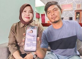 MOHD. Fadly Zakaria (kanan) dan Rosniza Hussin menunjukkan gambar Muhammad Farhan Mohd. Fadly yang berada di Unit Rawatan Rapi (ICU) Hospital Melaka selepas ditidurkan kerana komplikasi kesihatan.
