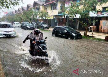 PENDUDUK menunggang motosikal melalui jalan yang dinaiki air di Meulaboh, Aceh Barat. - AGENSI
