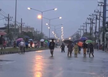 PENDUDUK melintasi jalan yang dinaiki air di daerah Muang, Songkhla berikutan hujan lebat. - ASSAWIN PAKKAWAN