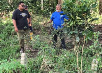 MOHD. Farid Mohd. Nor (kiri) bersama seorang penduduk kampung melihat kubur lama yang sebahagiannya sudah dihakis akibat runtuhan tebing Sungai Jelai di Tanjung Betong di Lipis, Pahang. – UTUSAN/HARIS FADILAH AHMAD