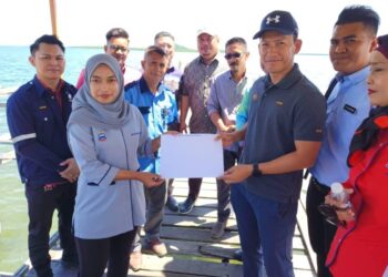PENGARAH KKDW Wilayah Sabah, Johar Julasbi (tiga kanan) menyerahkan surat arahan pelaksanaan kepada Penolong Pegawai Daerah Semporna, Intan Rahimah Kabimbangan di Jeti Pulau Bababag, Semporna hari ini.