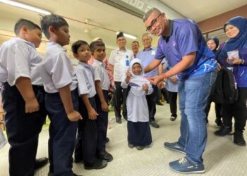 MOHD. RAZMAN Yaacob menyerahkan beg sekolah dan sumbangan wang tunai kepada pelajar Sekolah Kebangsaan Pulau Aman, Butterworth, Pulau Pinang hari ini.
