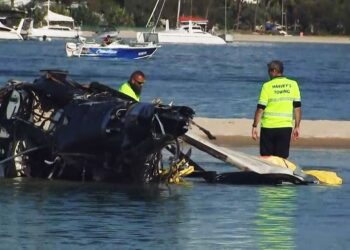 KAKITANGAN lapangan terbang mengalihkan serpihan helikopter yang terhempas berhampiran Gold Coast di Queensland semalam.-AFP