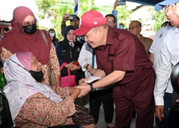 HAJIJI Noor menyampaikan bantuan kepada salah seorang mangsa fenomena air pasang besar di Kampung Tanjung Aru Baru di Kota Kinabalu hari ini.