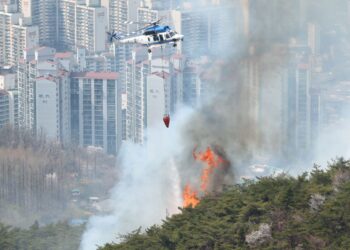 HELIKOPTER bomba melepaskan air bagi memadamkan kebakaran di Gunung Inwangsan di Seoul. - AFP