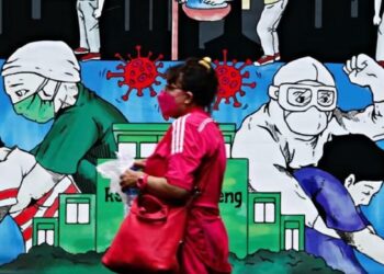 SEORANG wanita memakai pelitup muka berjalan melepasi lukisan mural yang mempromosikan kesedaran tentang wabak Covid-19 di Jakarta.-AGENSI