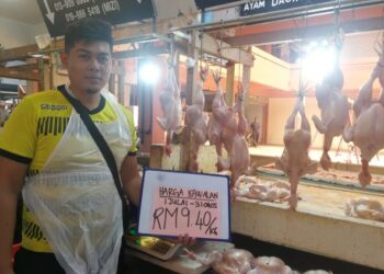 MOHD. Shahrul Nizam Mohd. Zamizi menunjukkan harga ayam yang dijual di Pasar Besar Dungun, Terengganu. - UTUSAN/NIK NUR IZZATUL HAZWANI NIK ADNAN