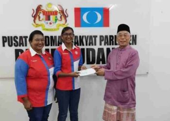 HASSAN Abdul Karim (kanan) menyampaikan sumbangan kepada penerima dalam satu majlis di Pusat Khidmat Rakyat Parlimen Pasir Gudang, baru-baru ini.