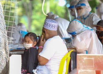 SEORANG penduduk dipakaikan gelang merah jambu selepas melakukan ujian saringan awal di penempatan Bukit Malut, Langkawi baru-baru ini. - UTUSAN/SHAHIR NOORDIN