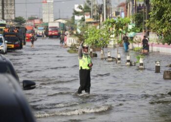 PEGAWAI Penguatkuasa mengawal lalu lintas di jalan Pantura Kaligawe di Semarang yang dilanda banjir.-AGENSI