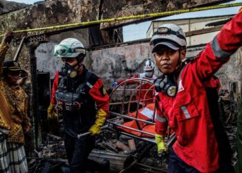 ANGGOTA bomba mengeluarkan mayat penduduk dari kawasan perumahan berhampiran depoh bahan api yang terbakar di Plumpang, Jakarta. - AFP   