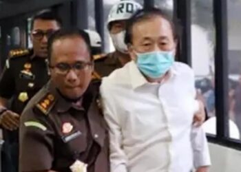 SURYA Darmadi (kanan) dibawa anggota polis selepas tiba di Mahkamah Jakarta baru-baru ini.-AGENSI