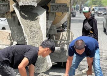 BAMBANG (kanan) bersama rakannya membaiki lubang di kawasan Jalan Parit Indah di Pekanbaru, Riau minggu lalu.-AGENSI