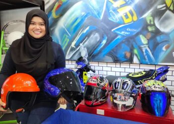 SITI Rahmah Abdol Rahim menunjukkan sebahagian koleksi topi keledar yang ditawarkan untuk dijual di kedai Abam 46 miliknya di Bazar Tampin Square, Tampin.-UTUSAN/NOR AINNA HAMZAH.