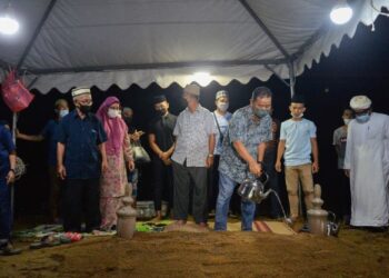 AHMAD Shapawi Ismail menyiram pusara Allahyarham Zolkples Embong di Tanah Perkuburan Islam Syed Yahya, Dungun, malam ini. - PUQTRA HAIRRY ROSLI