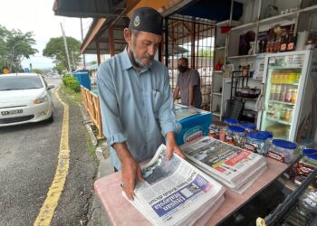 SYED Hassan Syed Abu Bakar menyusun akhbar Utusan Malaysia dan Kosmo! yang diterimanya untuk dijual di gerainya di Jalan Persiaran Putra, Kuah, Langkawi. – UTUSAN/NUR AMALINA AZMAN