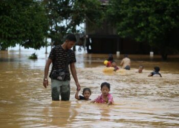 SEORANG penduduk membawa anak-anaknya mengharungi banjir di Kampung Kubang Betong, Changlun, Kubang Pasu, Kedah. - UTUSAN/ SHAHIR NOORDIN