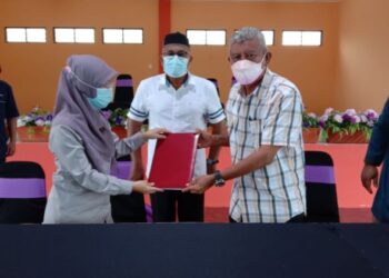 AHMAD NAZLAN Idris (berdiri, tengah) menyaksikan Khairun Nissa Aris (kiri) menyerahkan dokumen rasmi Dewan Orang Ramai kepada Rahman Yusof (kanan) di Taman Inderapura di Jerantut, Pahang. - UTUSAN/HARIS FADILAH AHMAD