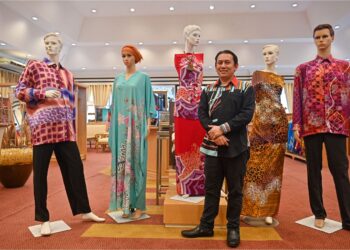 WAN Mohd. Hafiz Wan Mohd. Ariffin  bersama sebahagian daripada koleksi batik yang dipamerkan dan dijual  di Noor Arfa Craft Complex (NACC), Chendering, Kuala Terengganu.
