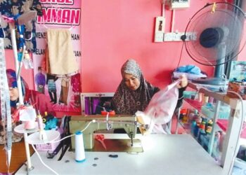JAKINAH Mohamed menyiapkan tempahan baju raya di kedainya di Taman Melur, Teluk Intan. – UTUSAN/AIN SAFRE BIDIN
