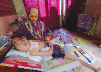 ASMAH Pik menjaga Nik Muhammad Faizul Izwan Nik Abdullah yang terlantar lumpuh di Kampung Machang, Ajil, Hulu Terengganu. 
– UTUSAN/NIK NOOR HAYATI MAMAT