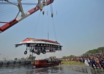 ORANG ramai menyaksikan pihak berkuasa mengeluarkan bangkai feri dari dalam air di Sungai Shitalakshya di Narayanganj, Bangladesh. - AFP