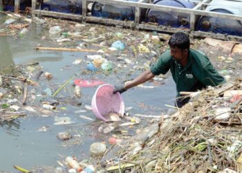 SEORANG pekerja kontrak bahagian pembersihan sungai sedang mengaut sisa sampah yang terperangkap di log boom Sungai Pinang, Georgetown di sini, tahun lalu. -UTUSAN/IQBAL HAMDAN