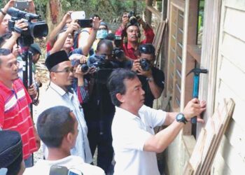 ABDULLAH Zawawi Kamaludin (belakang, bersongkok) mengiringi Al-Sultan Abdullah Ri’ayatuddin Al-Mustafa Billah Shah bergotong-royong membaiki rumah mangsa banjir pada awal Januari 2015 di Kampung Aur Gading di Lipis, Pahang.