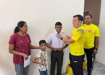 SOON LIP CHEE memperbetul pakaian sekolah S. Tharmarhaja ketika hadir menyerahkan surat tawaran dan bantuan kelengkapan persekolahan kepada remaja terbabit di rumahnya di Ampang Jajar, Butterworth, Pulau Pinang.