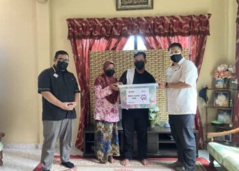 RAZLI Che Razak (kanan) menyerahkan sumbangan kepada Mohamad Firdaus Zamzu di Kampung Serungga, Pasir Mas, Kelantan semalam.