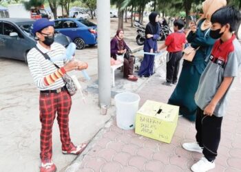 MOHD. Fahmi Mohd. Nazdri memakai kostum badut melayani kanak-kanak sambil meniup belon di Dataran 1Malaysia Klebang, Melaka. – UTUSAN/AMRAN MULUP