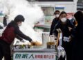 PENDUDUK membeli makanan di gerai tepi jalan selepas sekatan Covid-19 di Urumqi, wilayah Xinjiang dilonggarkan. - AFP