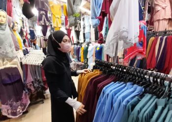 SYARIFAH Zainab Syed Abdul Karim menunjukkan baju raya yang dijual di kedainya di Bazar Kota, Kota Tinggi.