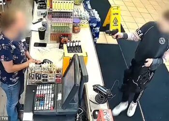 TANGKAP layar rakaman video menunjukkan suspek mengacukan pistol ke arah juruwang sebelum menuntut pekerja itu menyerahkan duit.  - WOODTV8
