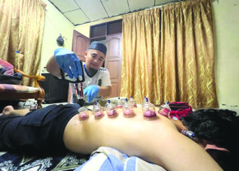 MOHAMMAD Shafik Ahmad Zuki menyediakan rawatan bekam untuk pelanggannya di Arau, Perlis. – UTUSAN/MOHD. HAFIZ ABD. MUTALIB