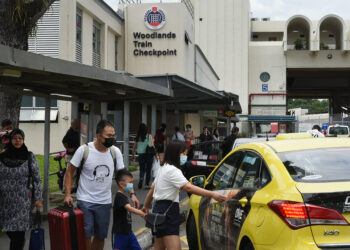 PENUMPANG memakai pelitup muka semasa menaiki teksi di hentian Woodlands, Singapura.-AFP
