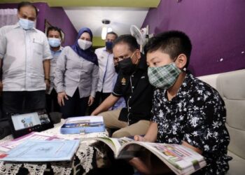REEZAL Merican Naina Merican melihat Muhammad Eiman Rafiqi Suhaimi, 9, menggunakan akses dan rangkaian internet secara percuma selepas Majlis Pelancaran Jendela@PPR di PPR Bersepadu Senawang, Seremban, hari ini.-UTUSAN/MOHD. SHAHJEHAN MAAMIN