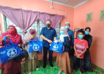 RIZAM Ismail (tengah) menyerahkan bantuan persekolahan kepada sebuah keluarga di Taman Air Manis, Sabak Bernam, Selangor hari ini.